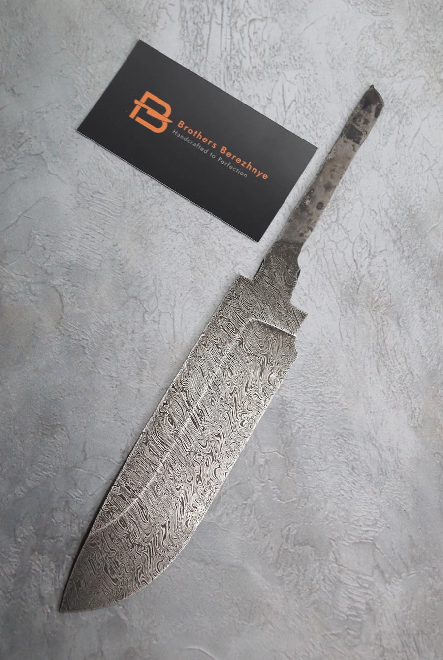 Hand-forged Damascus steel blade made from U8A, ShKh-15, 5KhNMA, and 45 steel – 85 mm length, etched finish Hand-forged Damascus steel blade made from U8A, ShKh-15, 5KhNMA, and 45 steel – 85 mm length, etched finish